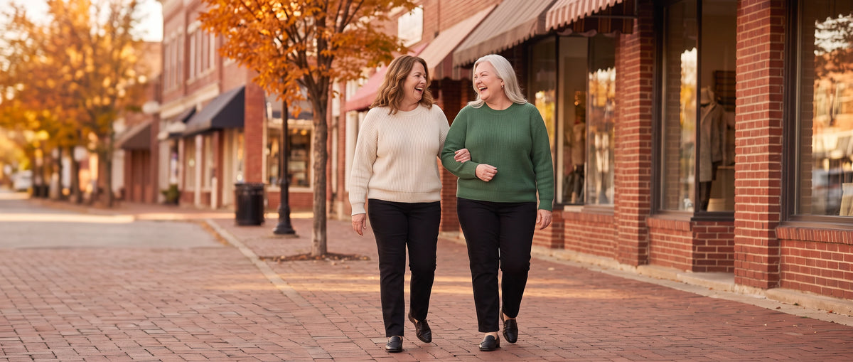 Clara and June, the founders of Clara & June, walking arm in arm down an autumn main street