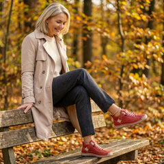 Rosie sneakers in red, worn while relaxing on a bench
