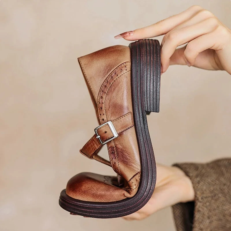 Hand flexing the sole of a Verda T-strap shoe in brown